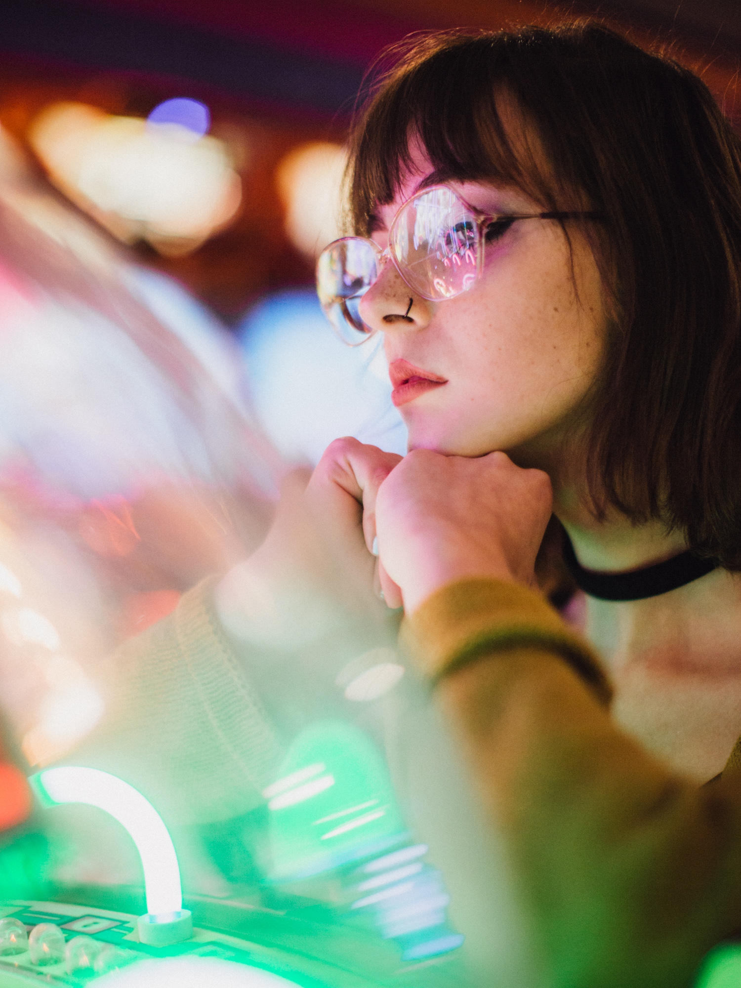 Portrait with glasses illuminated by colorful arcade lights