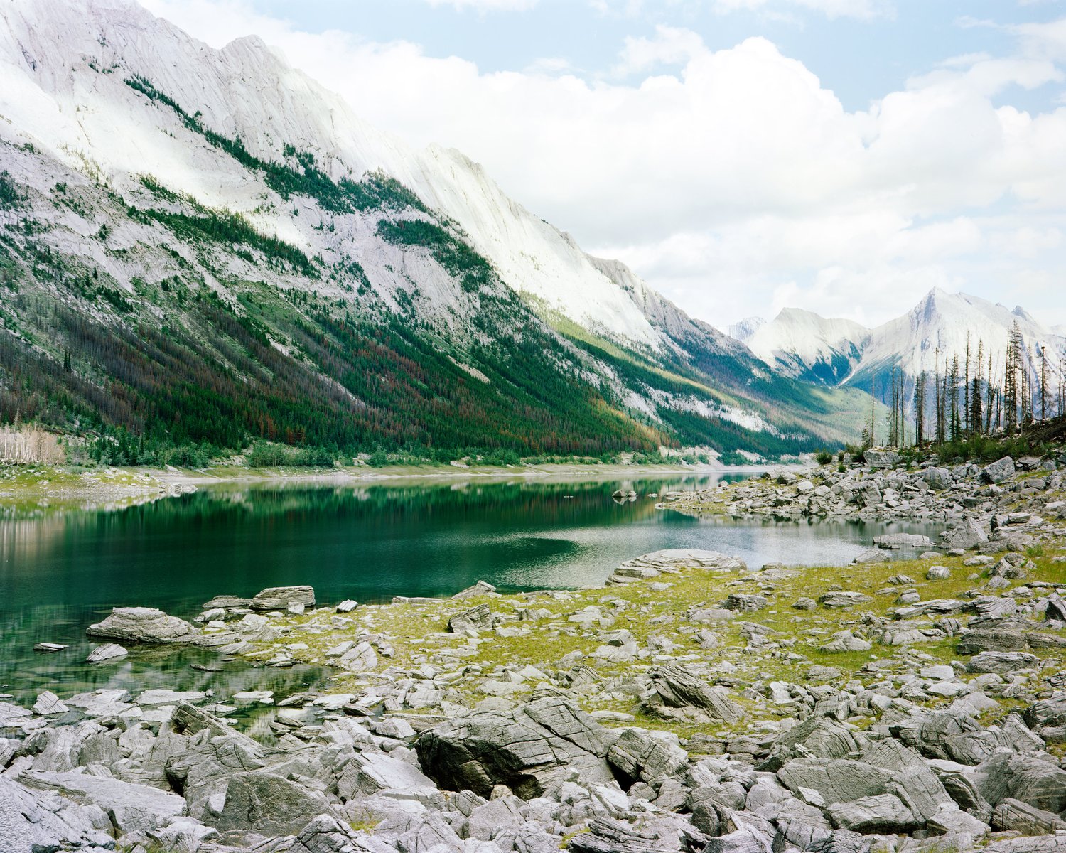 Mountain lake with a rocky shore and snowy peaks