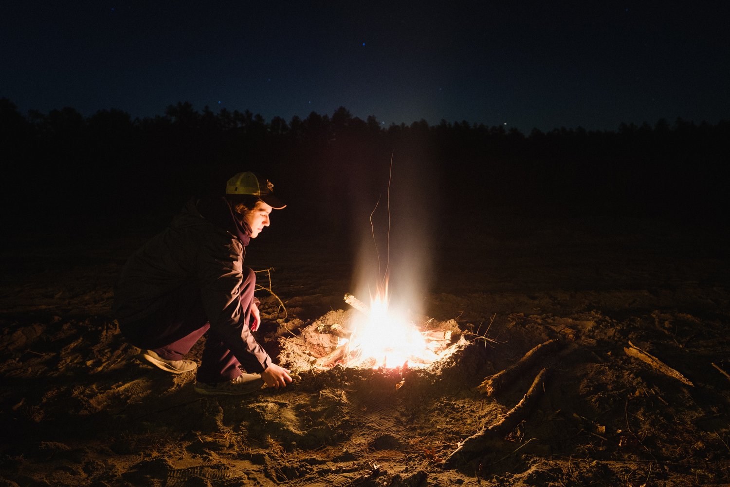 Person beside a campfire in a dark forest